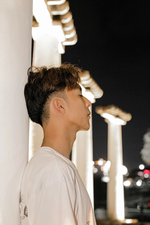 a boy standing next to a wall in front of buildings