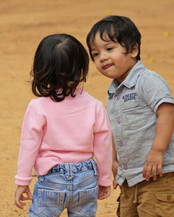 two children standing in dirt looking into each others eyes