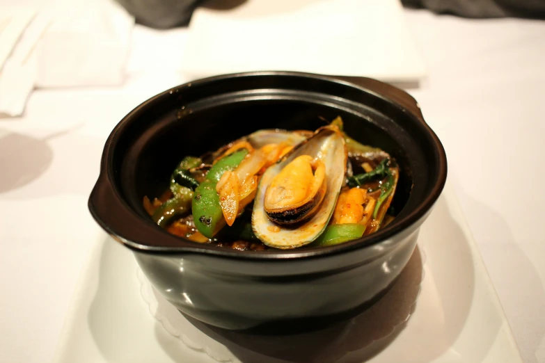 a small bowl is filled with mussels and vegetables