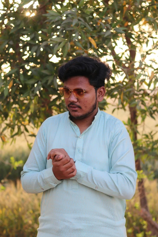 a man in a shirt is standing in front of some trees