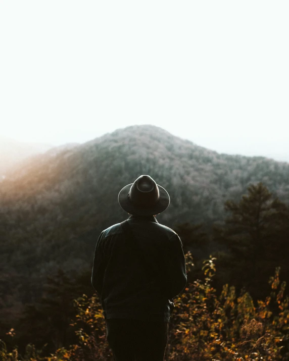 a person with a helmet and wearing coat standing in front of the mountains