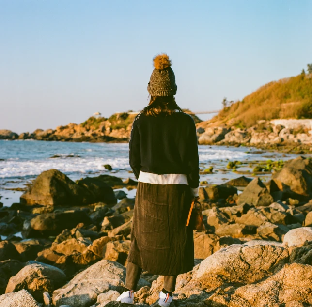 the woman is standing on the rocks at the beach