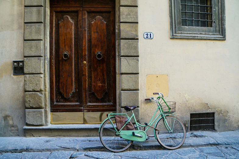 a green bicycle parked next to a building