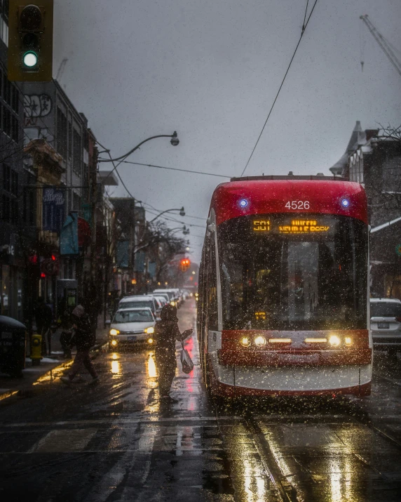 red city bus at a stoplight in the rain