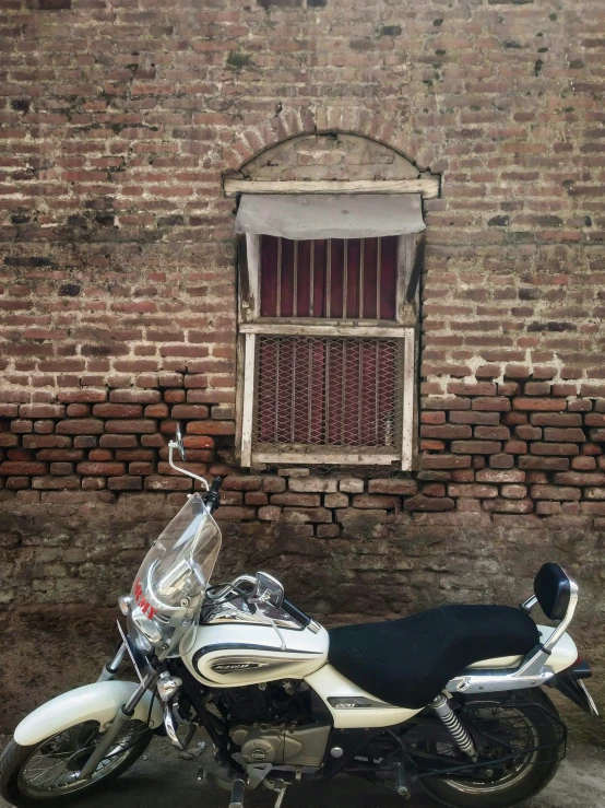a white motorcycle parked in front of a red brick building