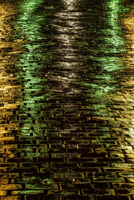 a brick walkway next to water with green lights