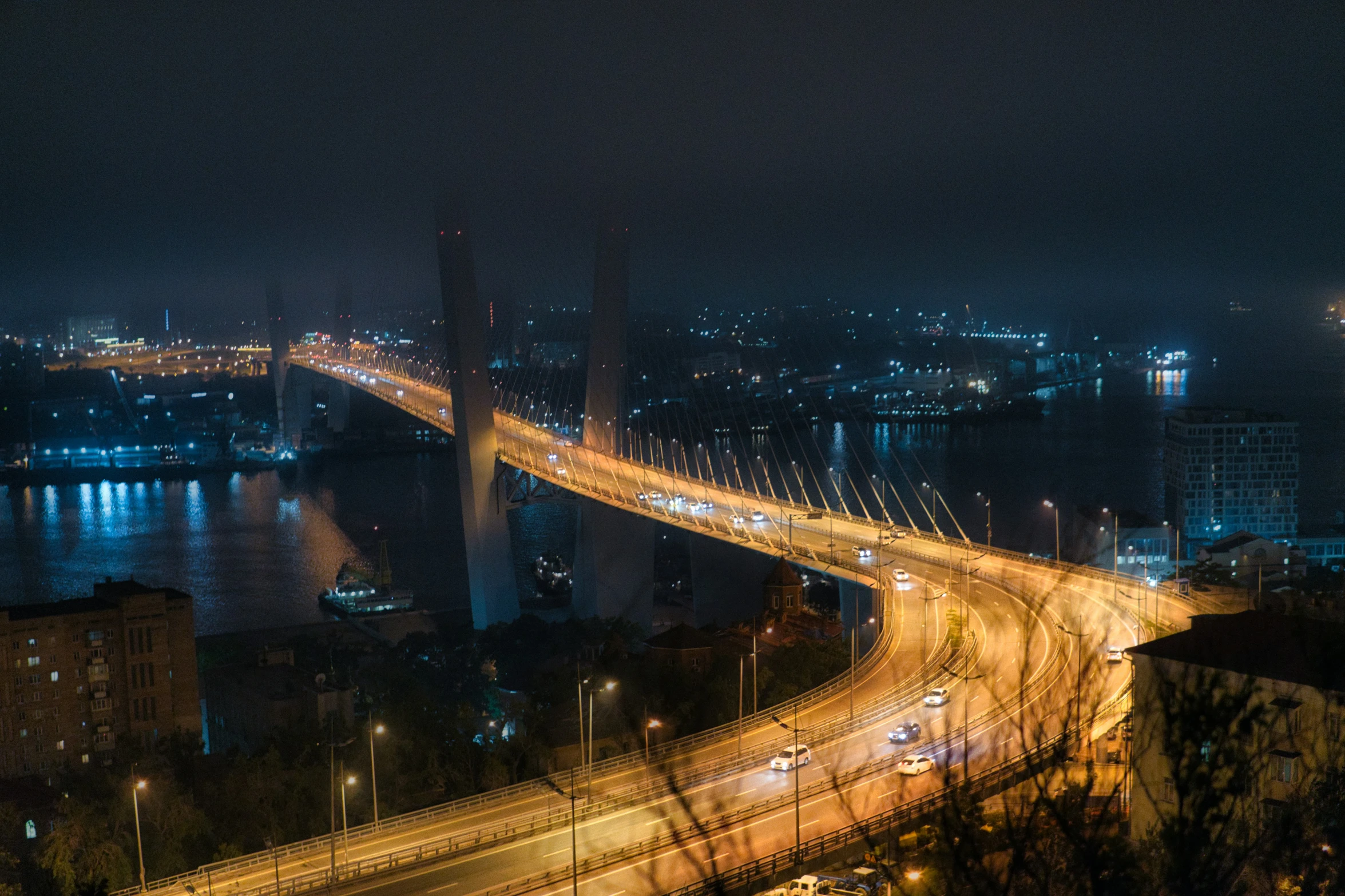 the city street with cars passing below a bridge