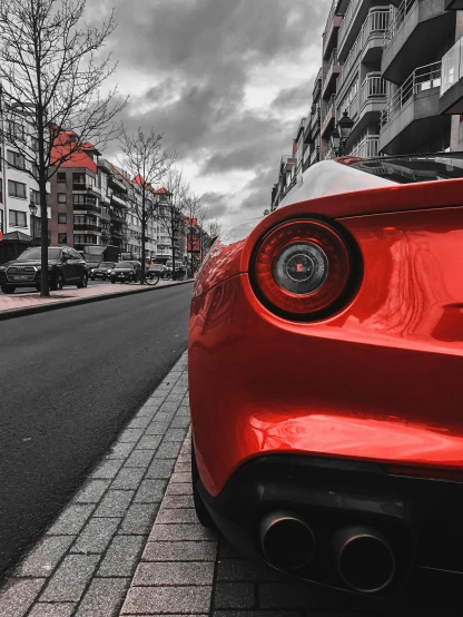 red sports car parked along the curb in front of an urban building