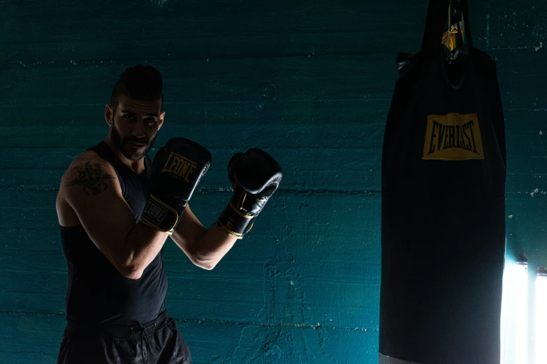 a man with black and white gloves stands in a dark gym