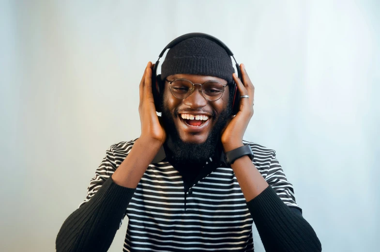 a man is smiling wearing headphones and holding his hands on one ear