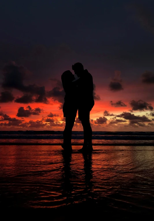 two people are standing near each other on a beach