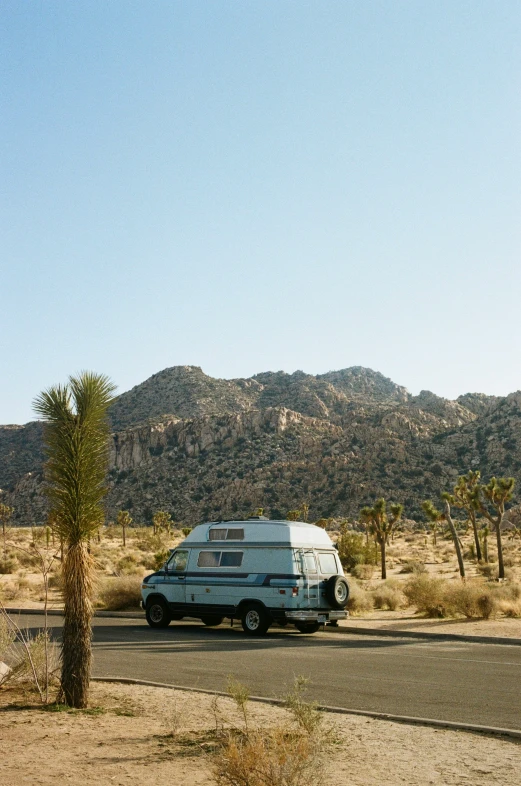 a van parked at the side of a road by mountains