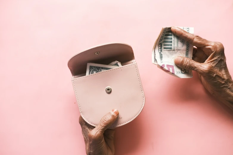 two hands holding a pink leather coin wallet