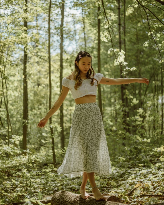 a  wearing a skirt standing on a log