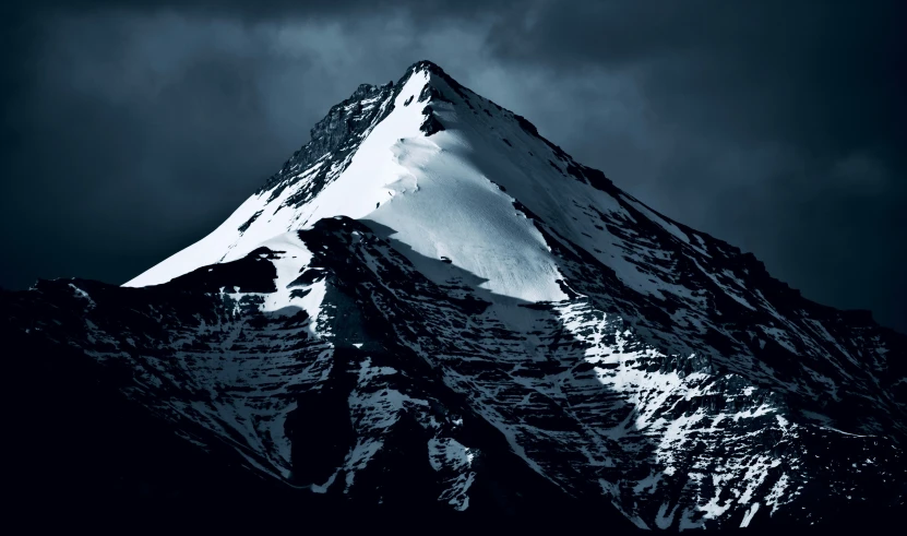 a high mountainside covered in snow and clouds