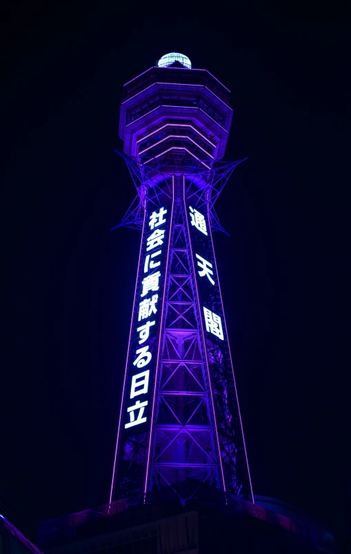 a tall tower lit up in the night with writing on it