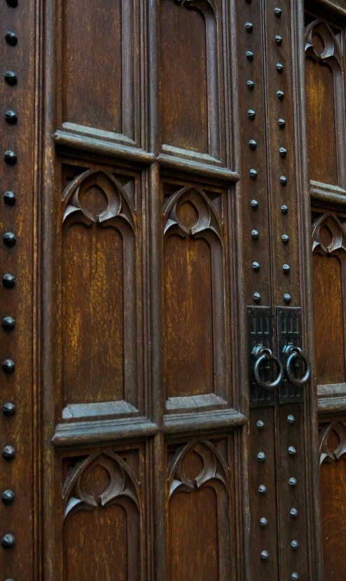 an old wooden door with metal knockers on it