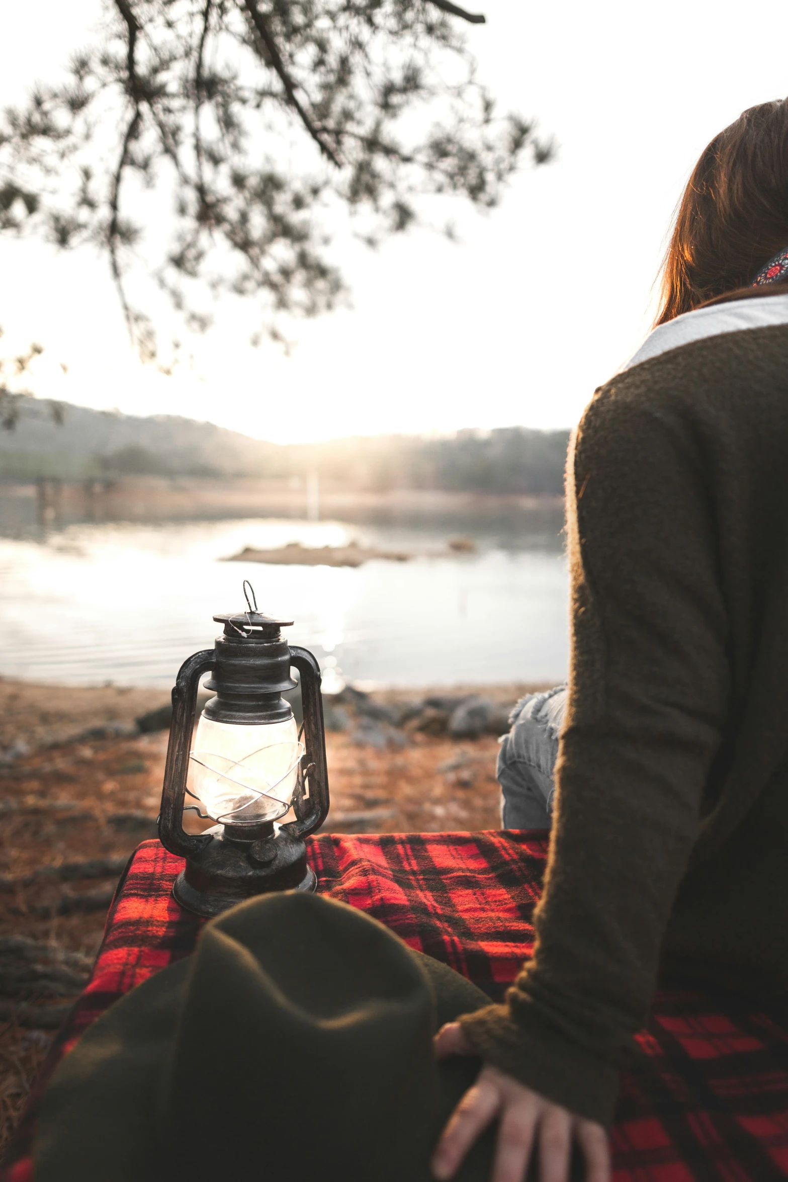 a woman is sitting down near a lantern that was placed on top of a table