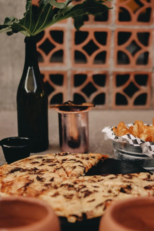 there is pizza sitting on the table with plates and cups next to it