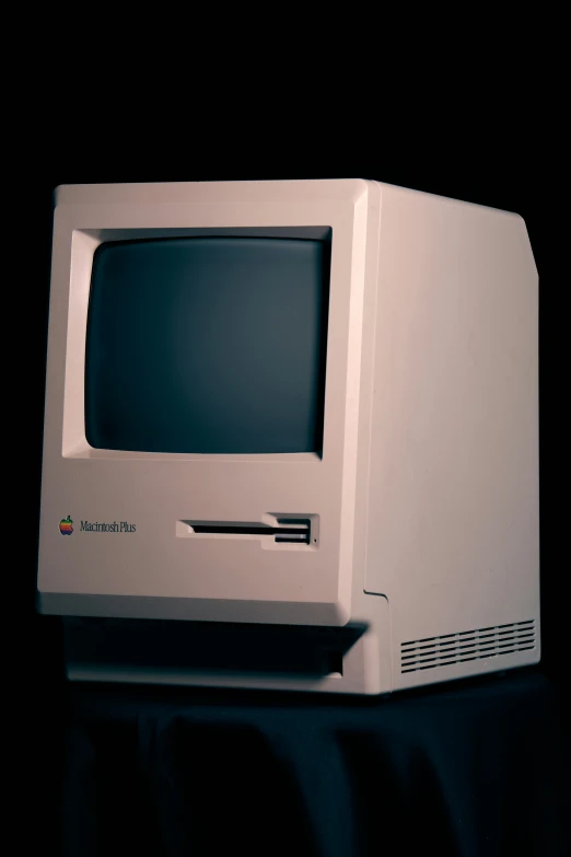 an old white macintosh computer in dark background