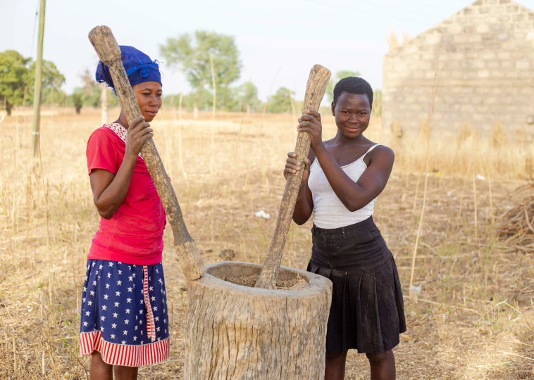 two woman standing next to a tree stump