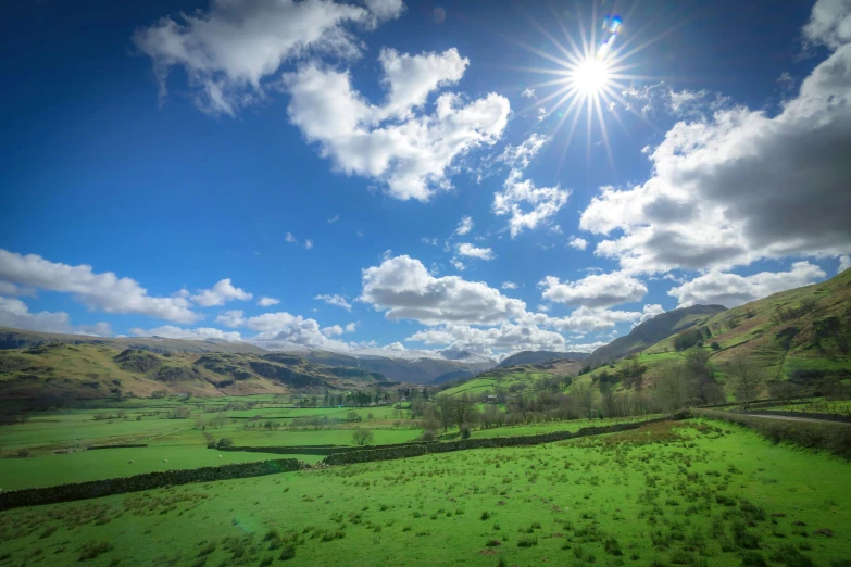 sun peeking over rolling mountains in the countryside