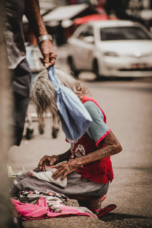 a woman sits on the street holding onto her umbrella