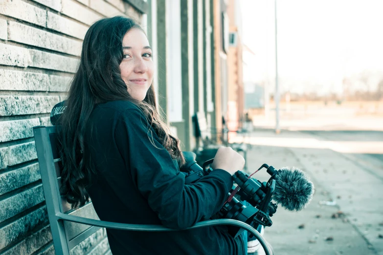 a girl standing near a building with a camera and microphone