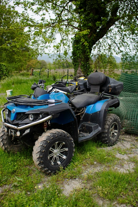two atv's parked next to a tree and fence