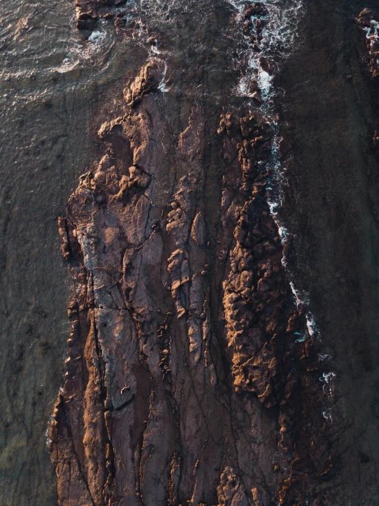 the sea is next to a large rock formation