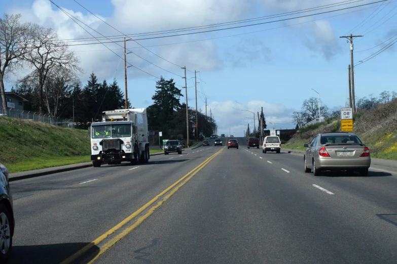 two trucks and a car on the road with traffic signs