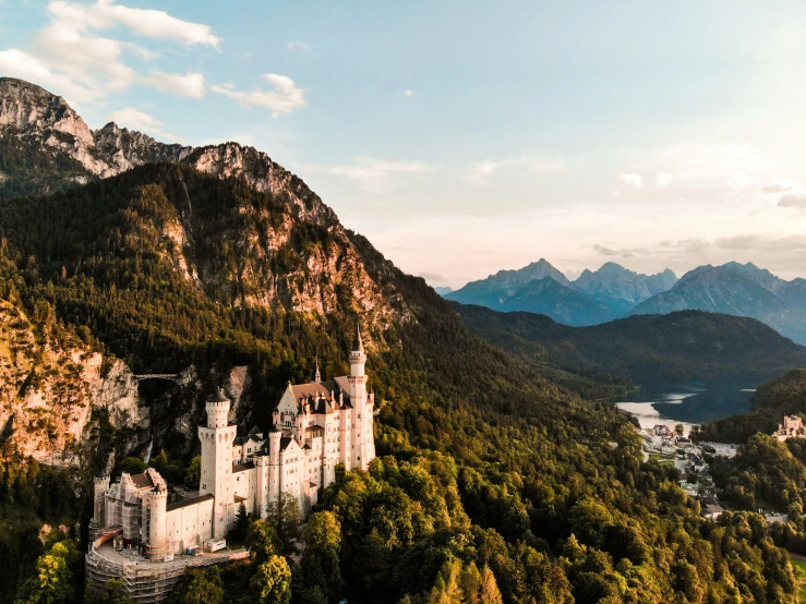 a castle with towers sits on the side of a mountain