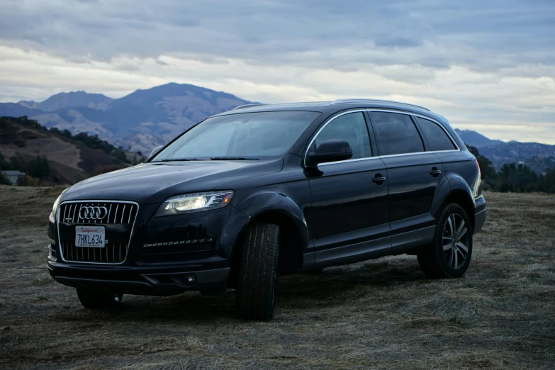 the suv is parked on a dirt field with mountains in the background