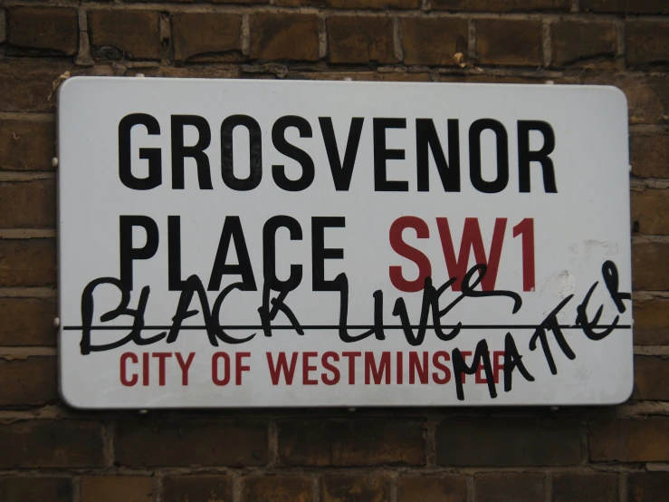 a sign posted on a brick wall saying grosvenor place sw1 black lives