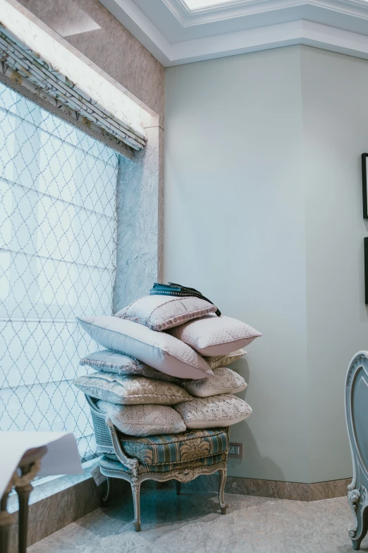 pillows sit on top of each other next to a mirror and chair