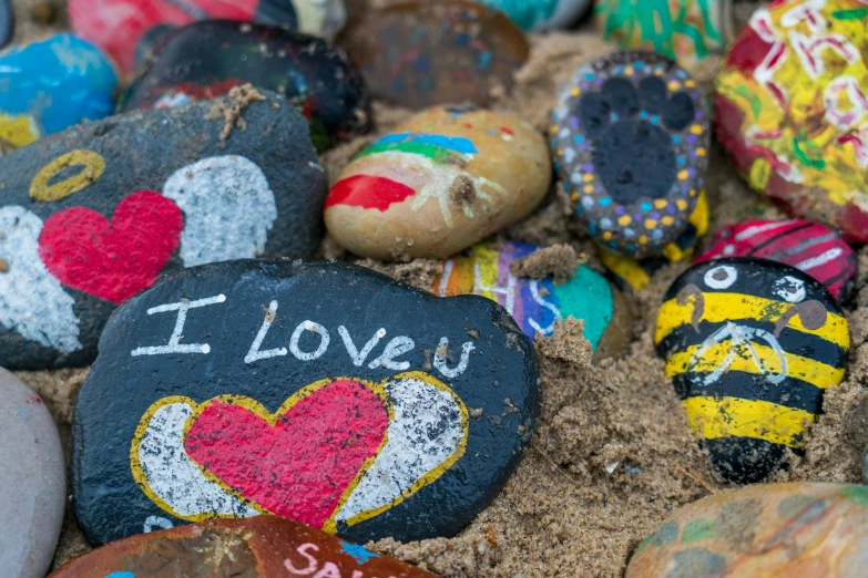 colorful rock art with a bee on the side and i love you painted on it