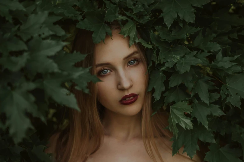 young woman surrounded by foliage with red lipstick