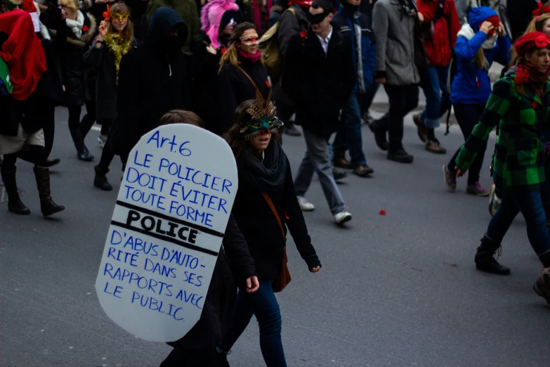 a woman carries a sign as she walks in the middle of a street