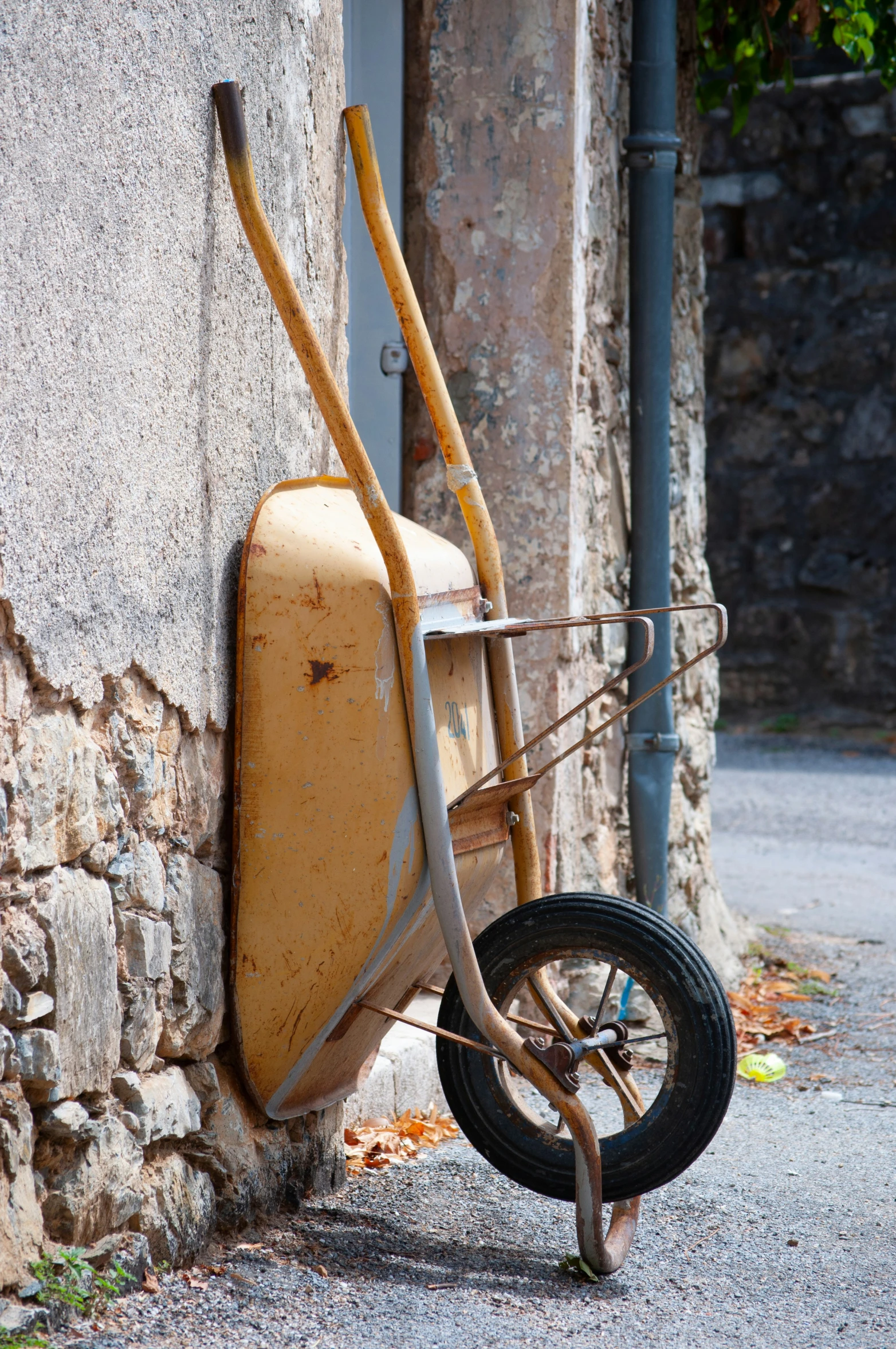 a wheelbarrow leaning against a stone building