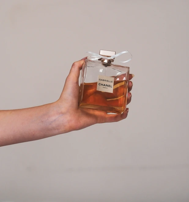 someone holding a small square shaped bottle with no label