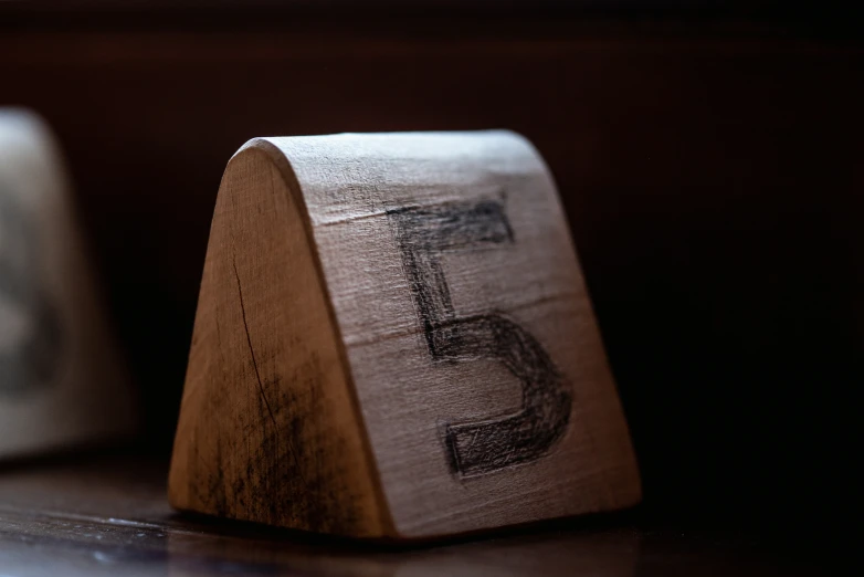 a small wooden block with the letter f written on it