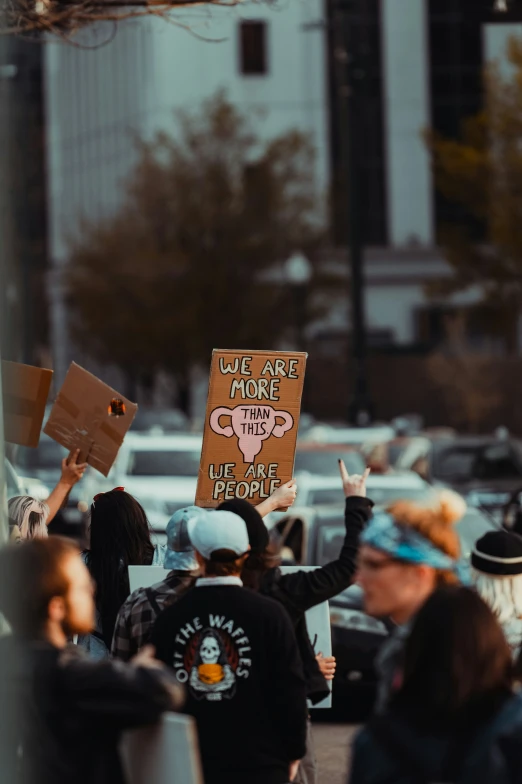 a group of protesters holding up signs on a street corner