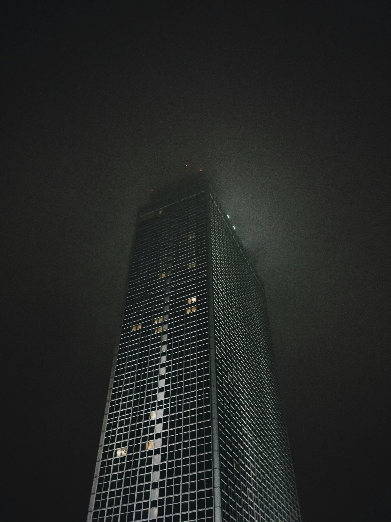 a tall building is seen from the ground at night