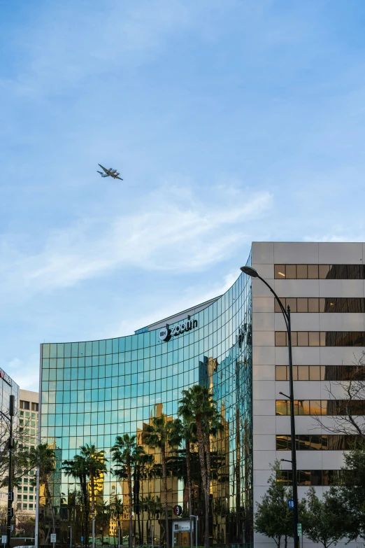 a passenger plane flying in front of a glass building