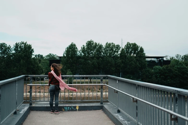 a girl that is holding a scarf on a bridge