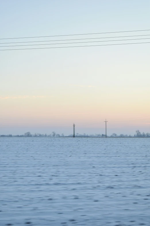 an empty beach under power lines with the sun setting