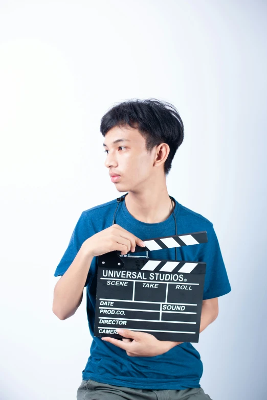 an asian man in blue holding a black and white clap board