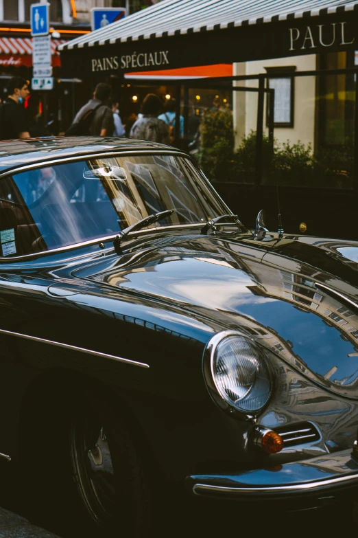 an antique black car sits in front of a store