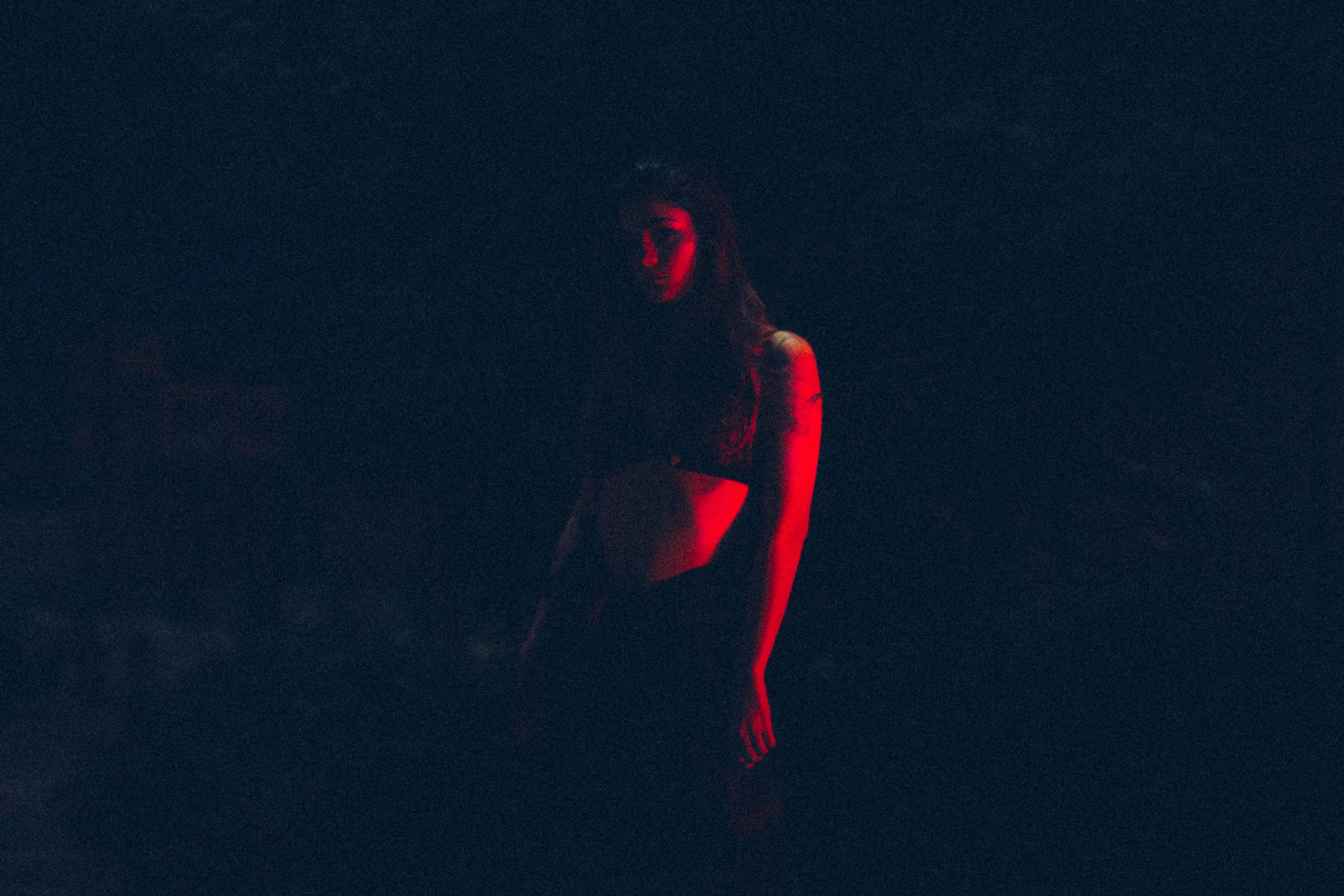 a young woman standing in the dark wearing a white bathing suit