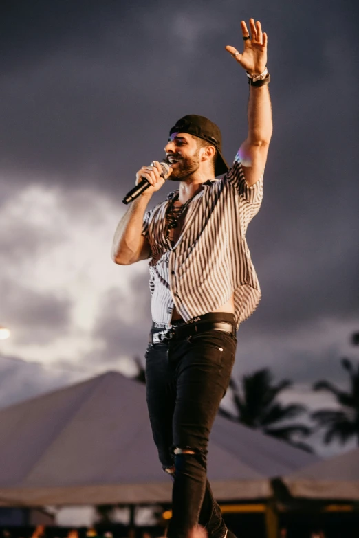 a man is performing on a stage wearing black pants and striped shirt